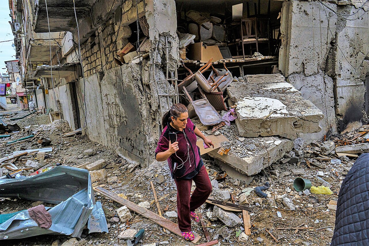 A woman walks beside a damaged residential building in Stepanakert after fighting in October 2020.